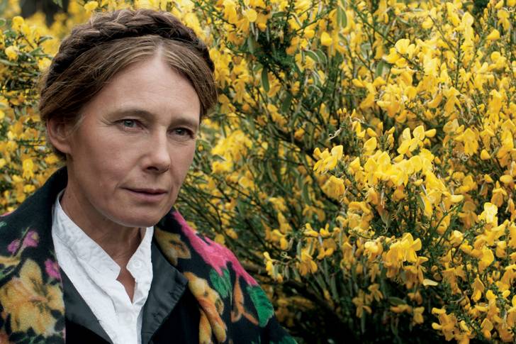 Close-up image of a woman's face against a field of yellow flowers.